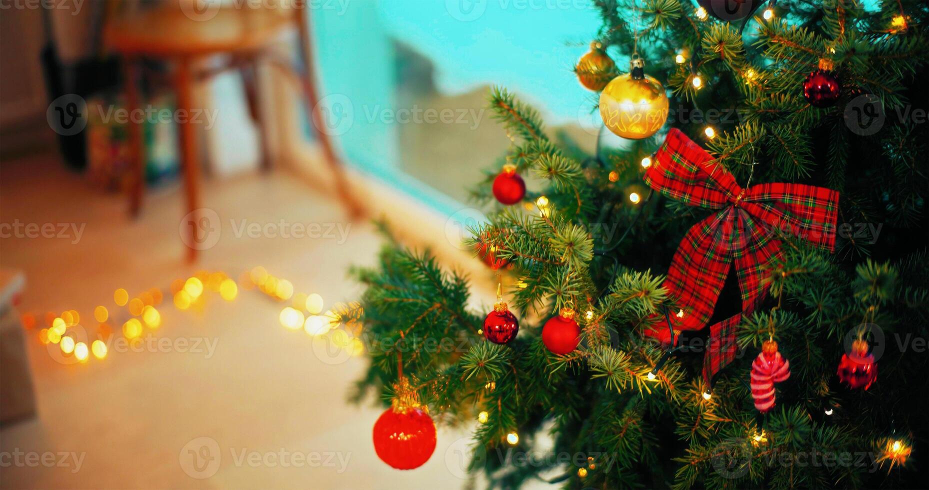 Christmas tree branch decorated with candy cane and baubles with blurred shiny lights on background photo