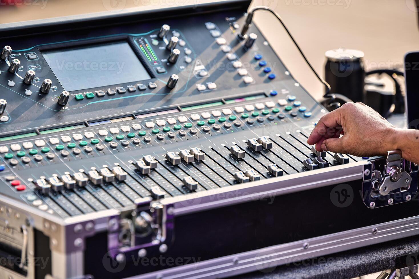 The DJ is adjusting the volume of the sound. Professional audio mixing console photo