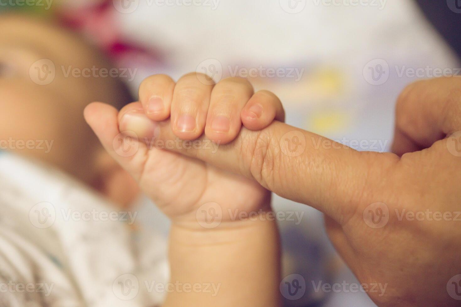 el manos de el madre sostener el del bebe mano con amor y cariñoso. foto