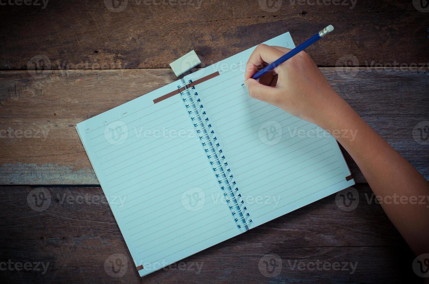 Hand writing in open notebook on table photo