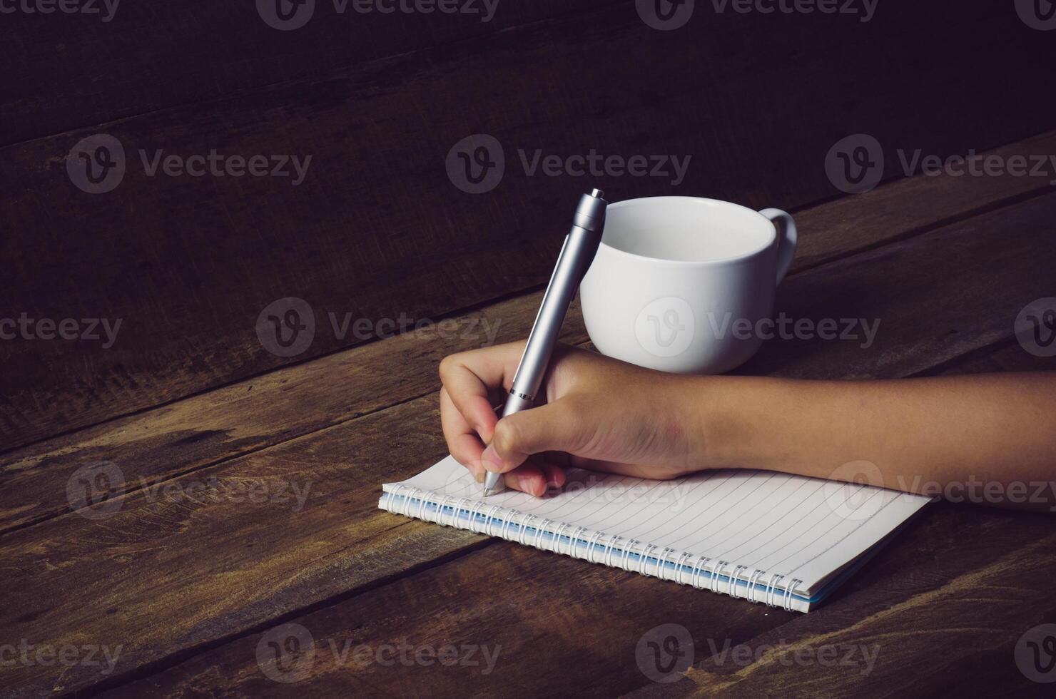 Hand writing in open notebook on table photo