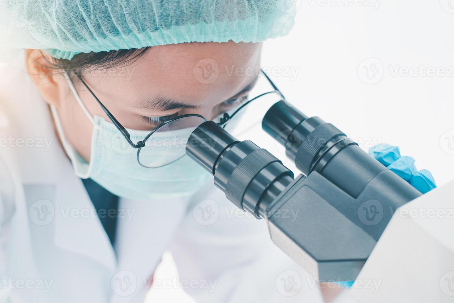 hembra médico investigador mirando a un microscopio en un médico laboratorio. médico experimental concepto foto