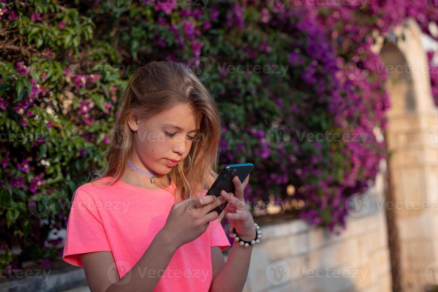 a young girl in a pink shirt is using her phone photo