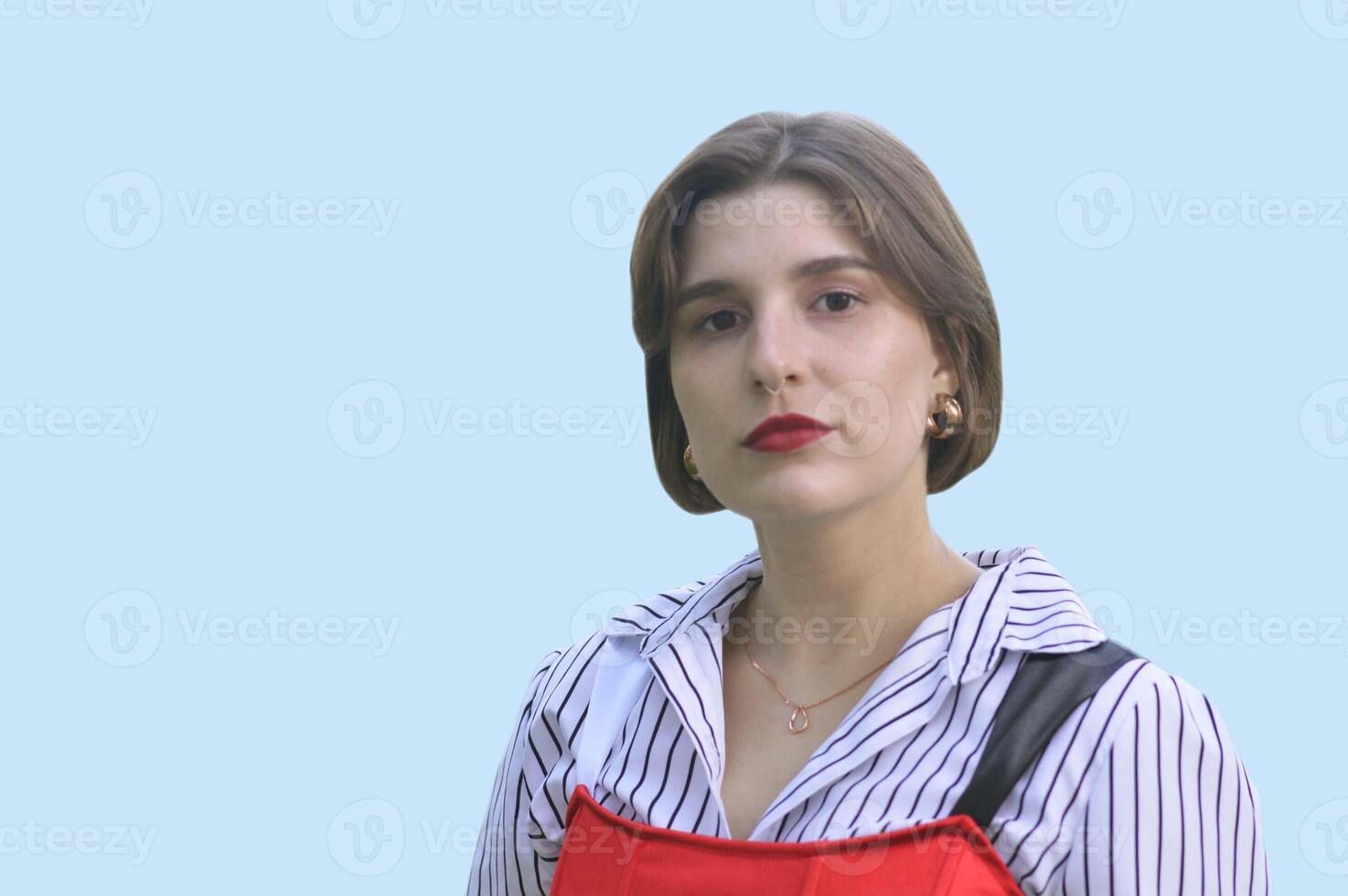Portrait of a young Caucasian girl wearing a fashionable red top and white shirt, isolated on a blue background. Place for text. photo