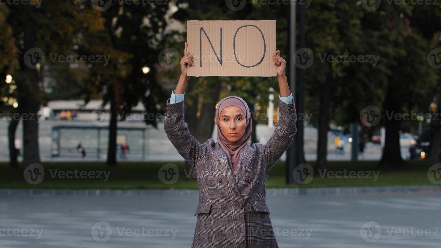 Stop racism concept Arab immigrant Muslim woman in hijab protests against discrimination vax vaccination standing in city. Islamic girl holding cardboard slogan banner with text no disagree refusal photo