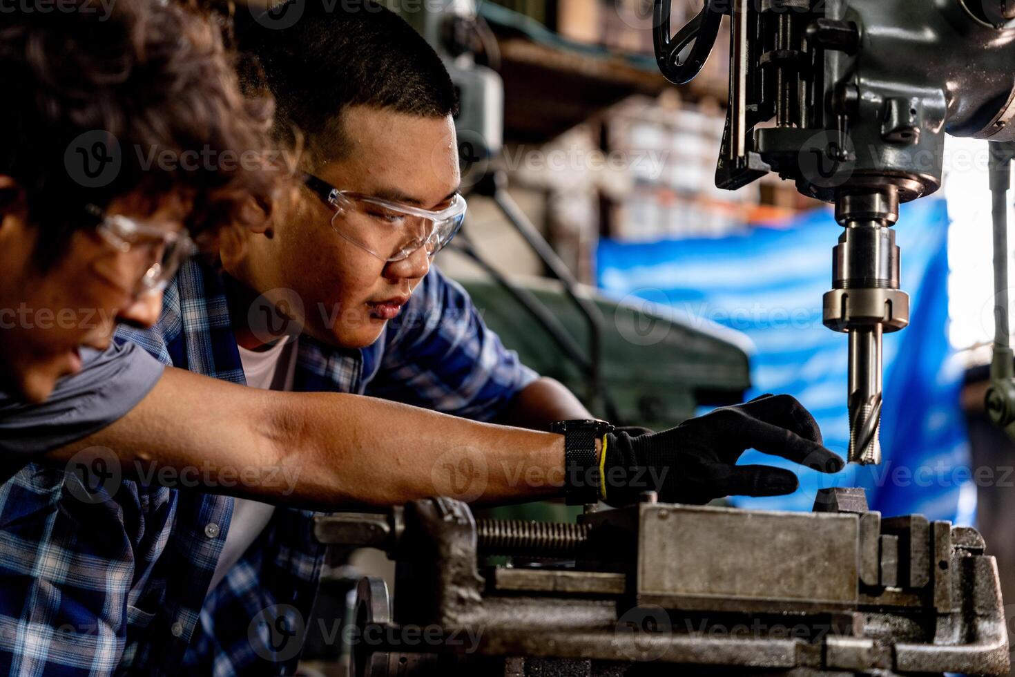 Asian worker in production plant drilling at machine. Professional worker near drilling machine on factory. finishing metal working internal steel surface on lathe grinder machine with flying sparks. photo