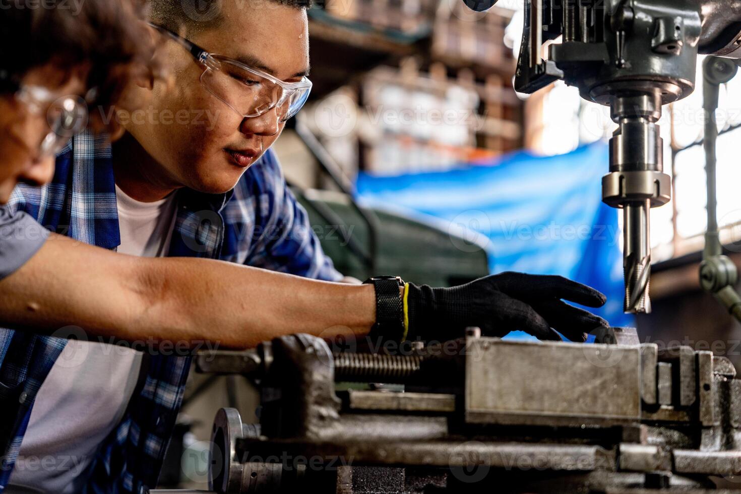 Asian worker in production plant drilling at machine. Professional worker near drilling machine on factory. finishing metal working internal steel surface on lathe grinder machine with flying sparks. photo