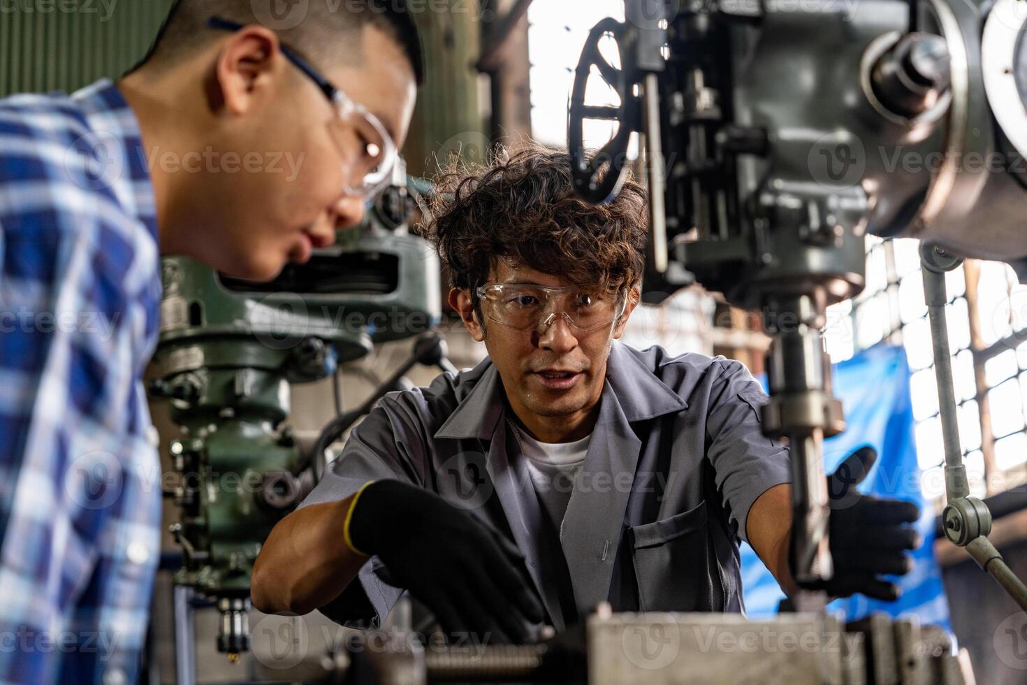 Asian worker in production plant drilling at machine. Professional worker near drilling machine on factory. finishing metal working internal steel surface on lathe grinder machine with flying sparks. photo