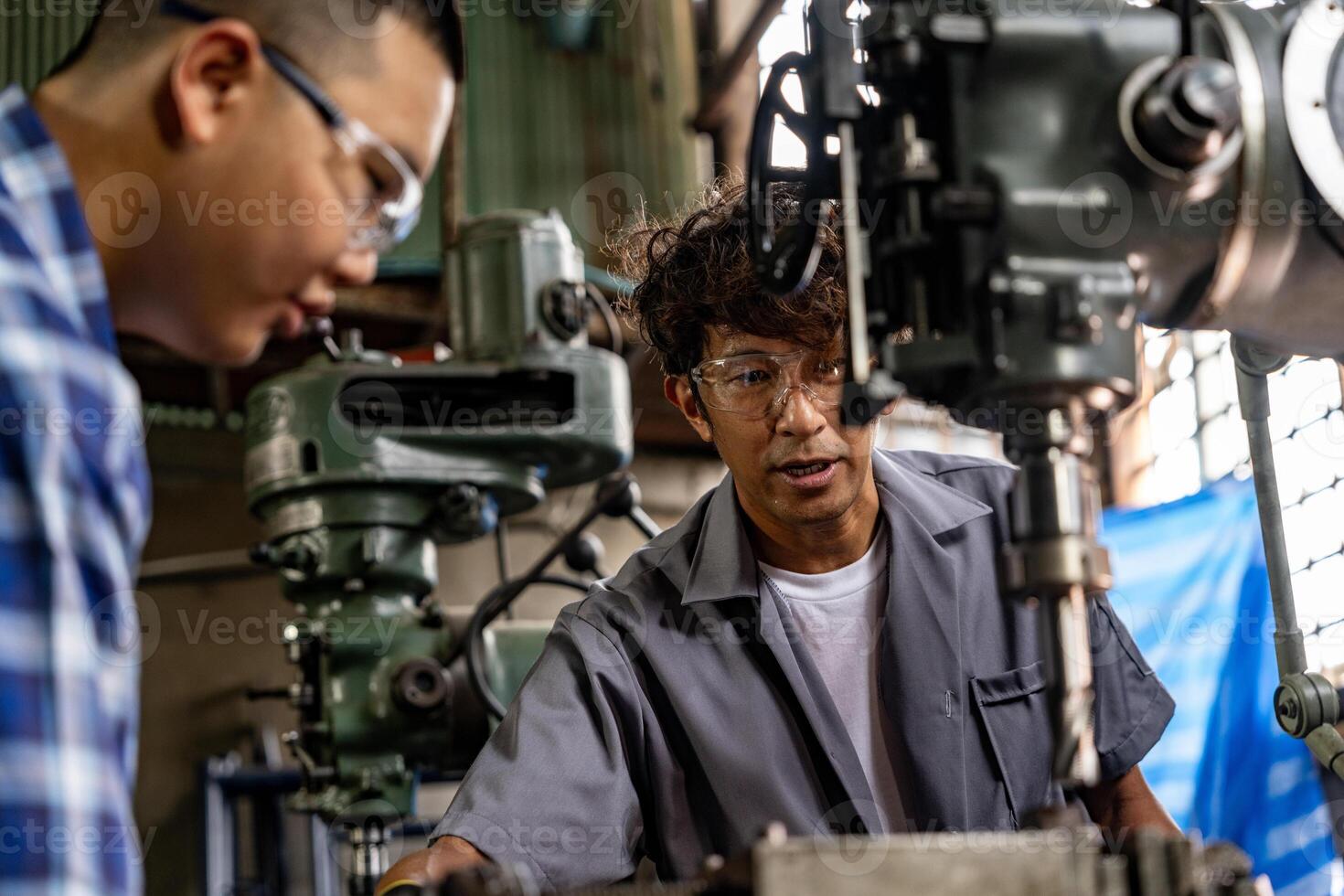 Asian worker in production plant drilling at machine. Professional worker near drilling machine on factory. finishing metal working internal steel surface on lathe grinder machine with flying sparks. photo