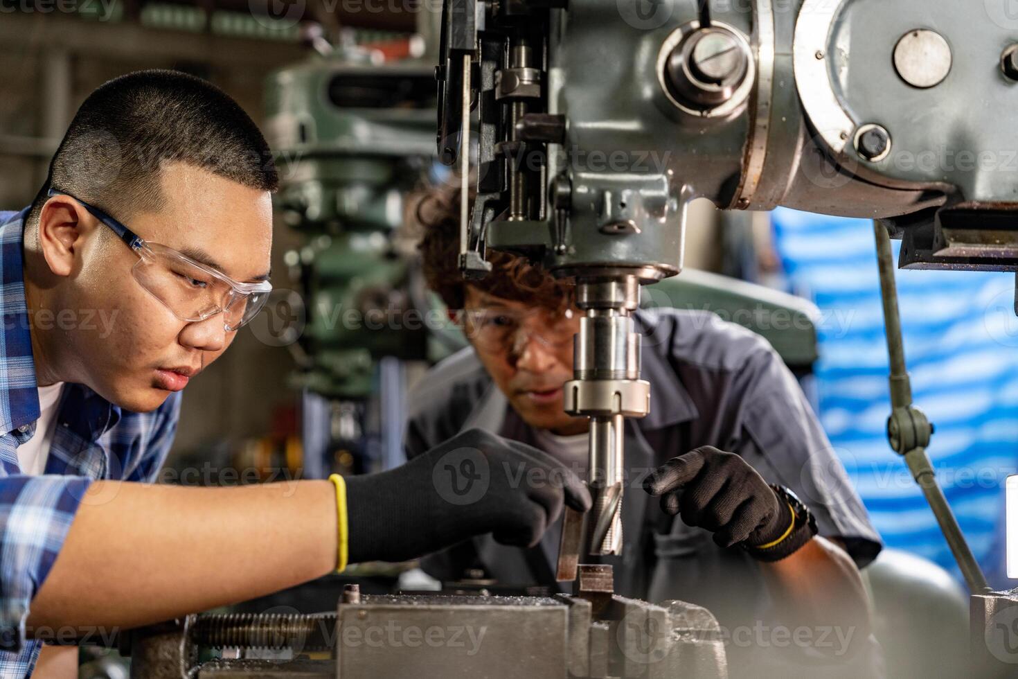 Asian worker in production plant drilling at machine. Professional worker near drilling machine on factory. finishing metal working internal steel surface on lathe grinder machine with flying sparks. photo