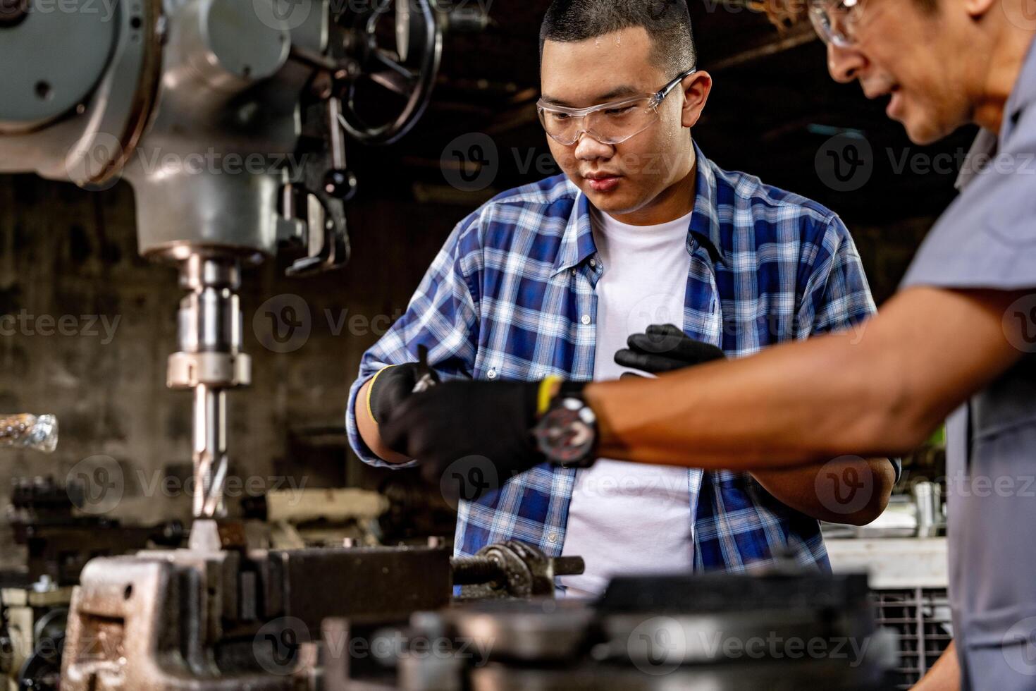 Asian worker in production plant drilling at machine. Professional worker near drilling machine on factory. finishing metal working internal steel surface on lathe grinder machine with flying sparks. photo