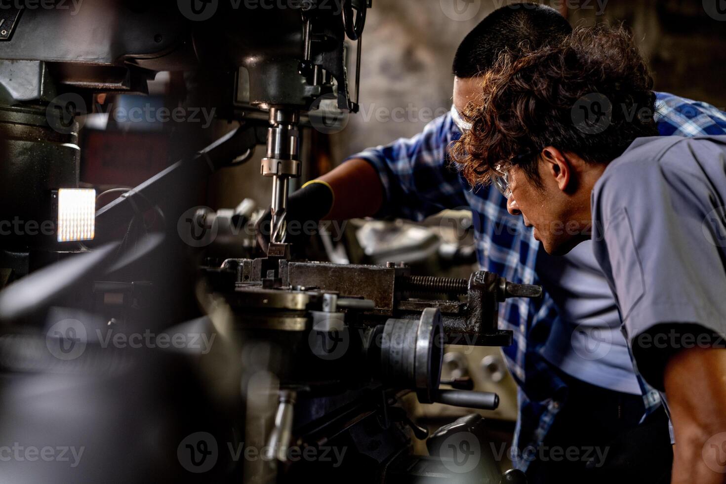 asiático trabajador en producción planta perforación a máquina. profesional trabajador cerca perforación máquina en fábrica. refinamiento metal trabajando interno acero superficie en torno amoladora máquina con volador chispas. foto