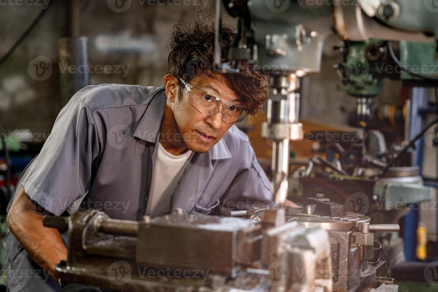 Engineer worker in production plant drilling at machine. Professional worker near drilling machine on factory. man inspecting and repairing machine for operation in workshop. photo