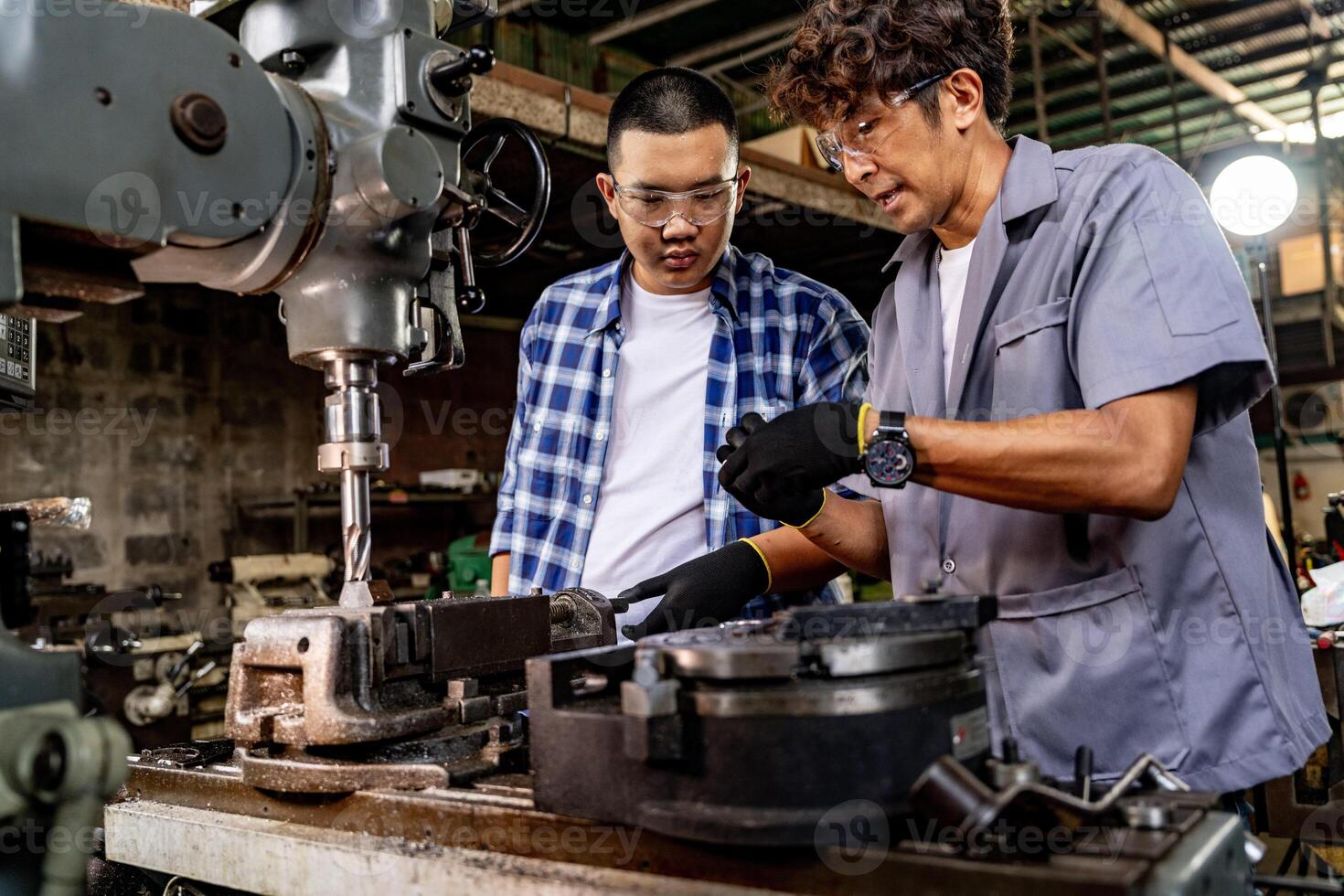 Asian worker in production plant drilling at machine. Professional worker near drilling machine on factory. finishing metal working internal steel surface on lathe grinder machine with flying sparks. photo