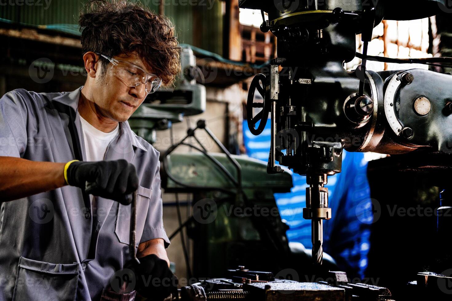 Engineer worker in production plant drilling at machine. Professional worker near drilling machine on factory. man inspecting and repairing machine for operation in workshop. photo