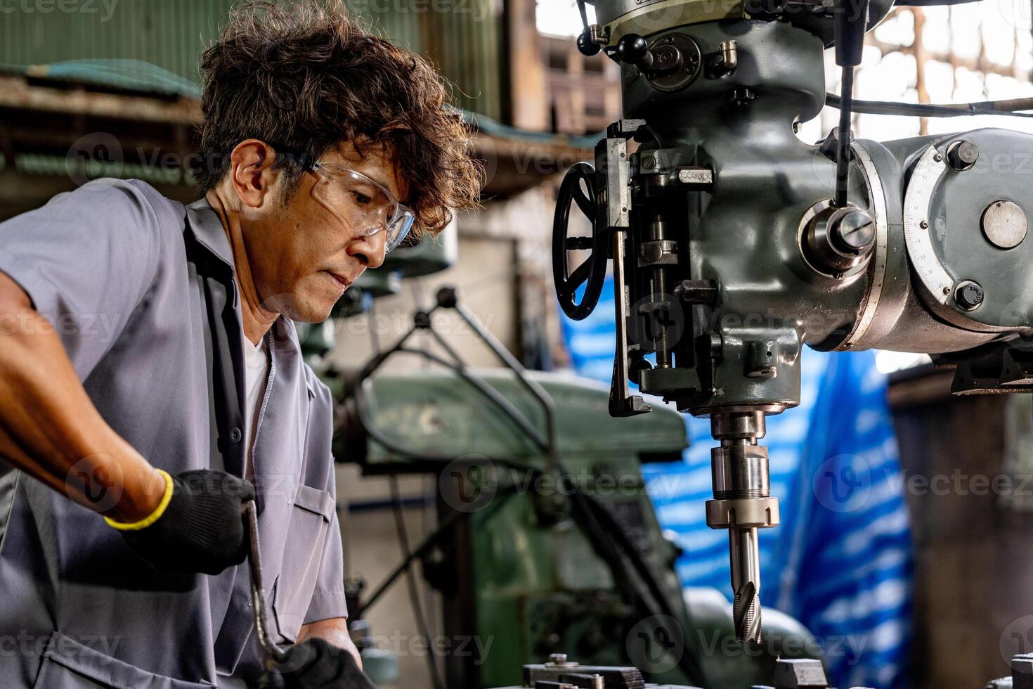 Engineer worker in production plant drilling at machine. Professional worker near drilling machine on factory. man inspecting and repairing machine for operation in workshop. photo