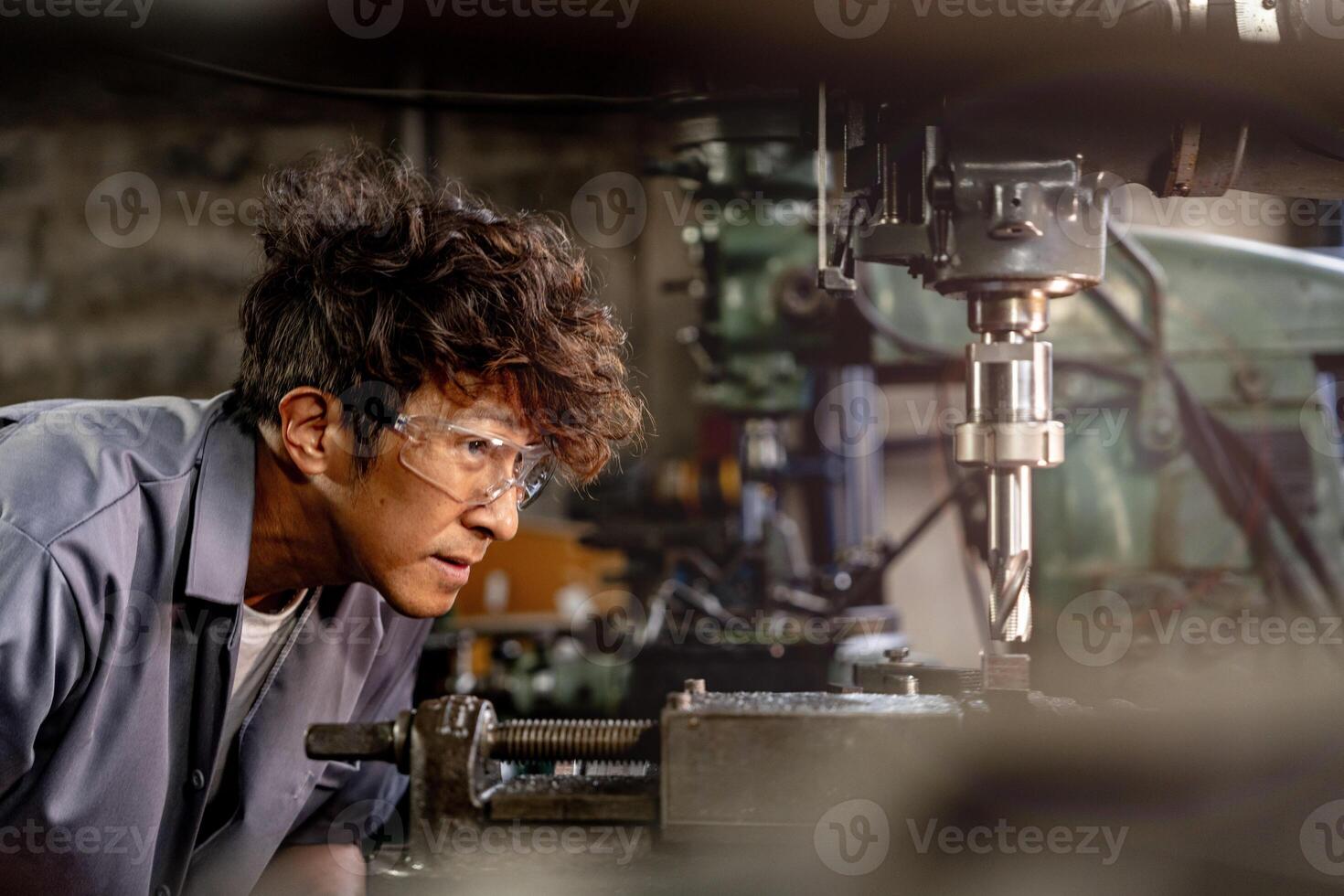 Engineer worker in production plant drilling at machine. Professional worker near drilling machine on factory. man inspecting and repairing machine for operation in workshop. photo
