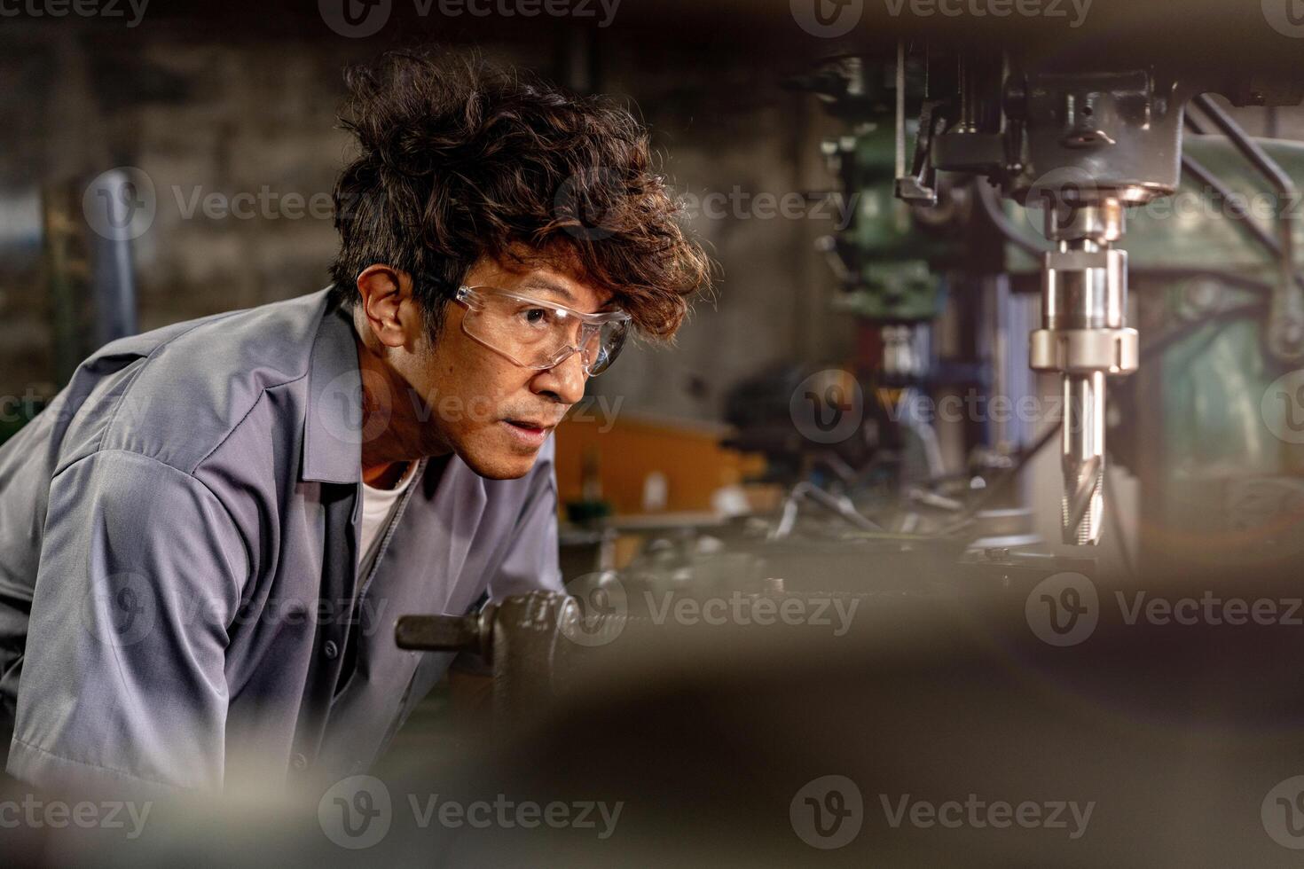 Engineer worker in production plant drilling at machine. Professional worker near drilling machine on factory. man inspecting and repairing machine for operation in workshop. photo