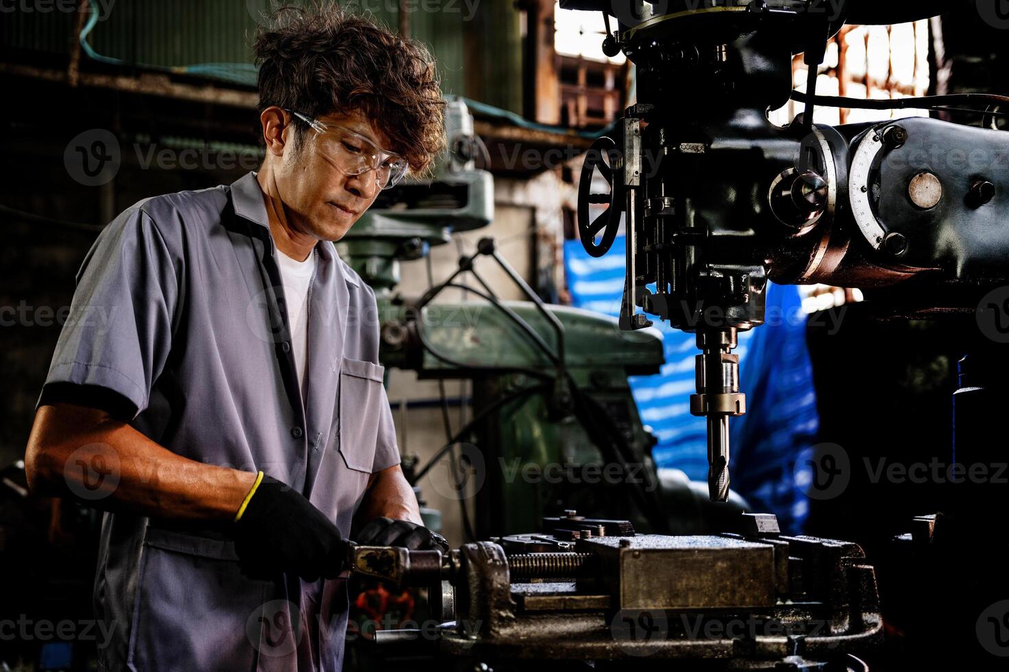 Engineer worker in production plant drilling at machine. Professional worker near drilling machine on factory. man inspecting and repairing machine for operation in workshop. photo