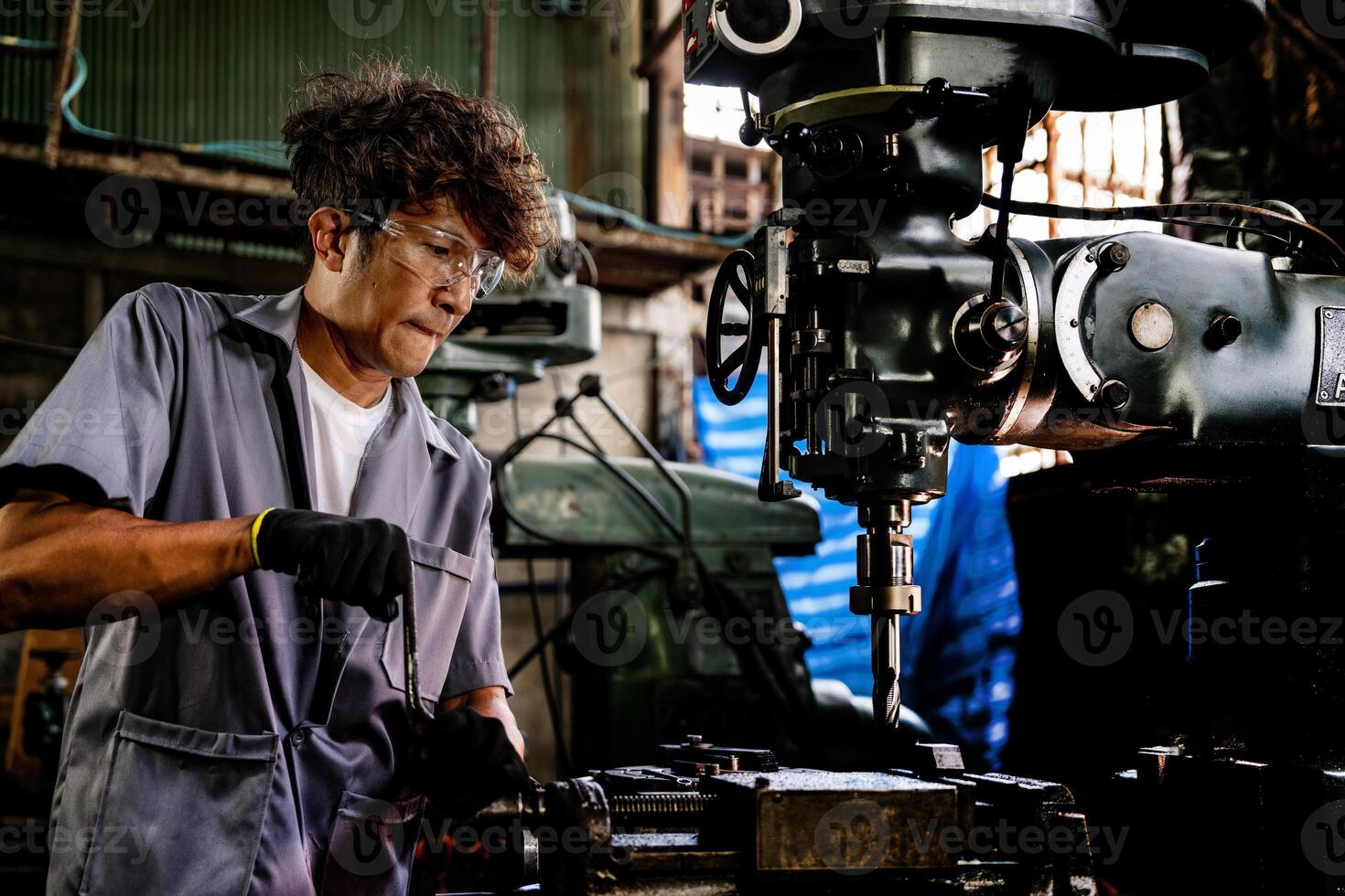 Engineer worker in production plant drilling at machine. Professional worker near drilling machine on factory. man inspecting and repairing machine for operation in workshop. photo