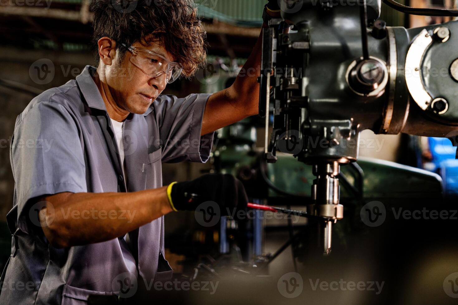 Engineer worker in production plant drilling at machine. Professional worker near drilling machine on factory. man inspecting and repairing machine for operation in workshop. photo