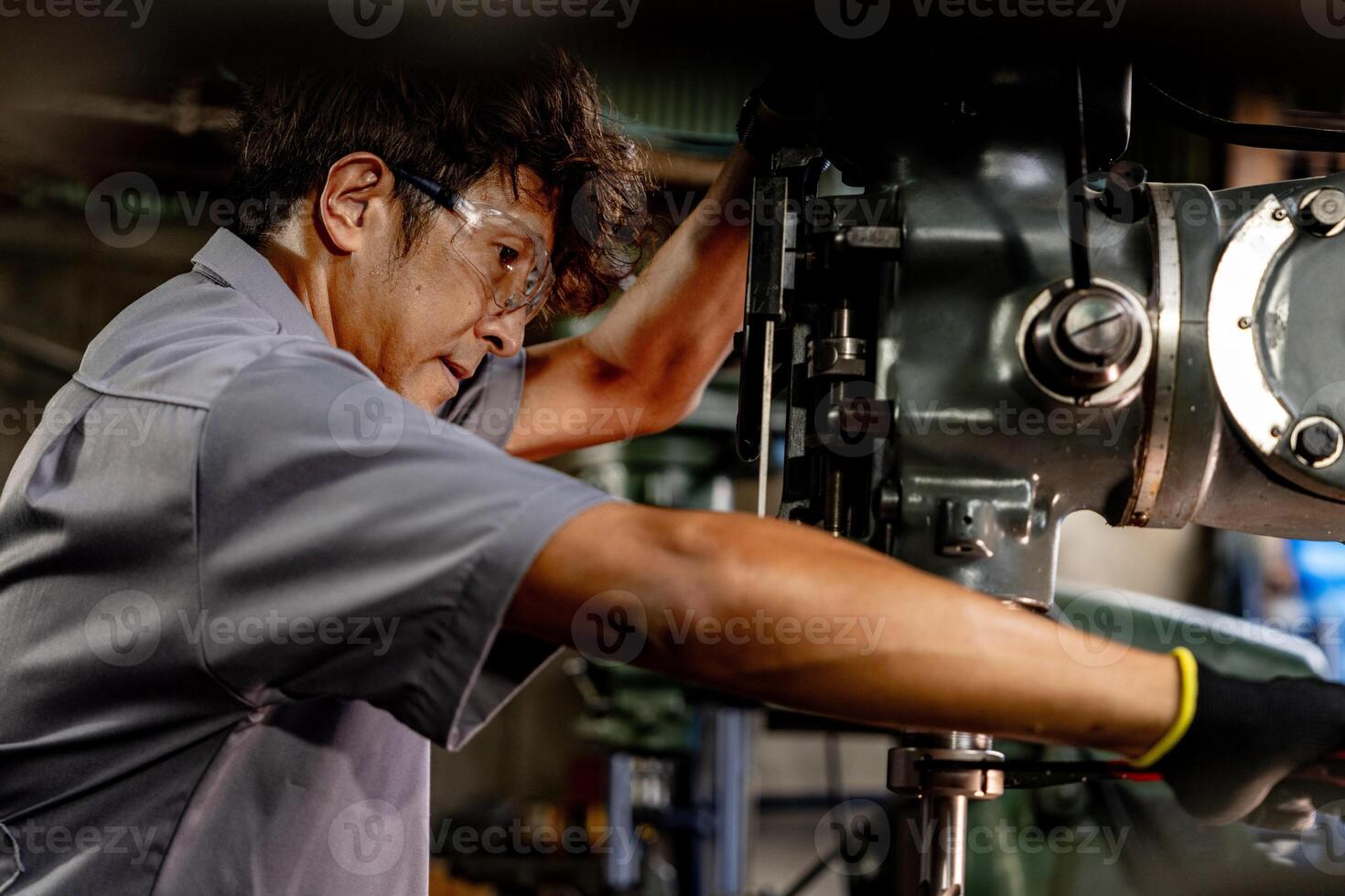 Engineer worker in production plant drilling at machine. Professional worker near drilling machine on factory. man inspecting and repairing machine for operation in workshop. photo