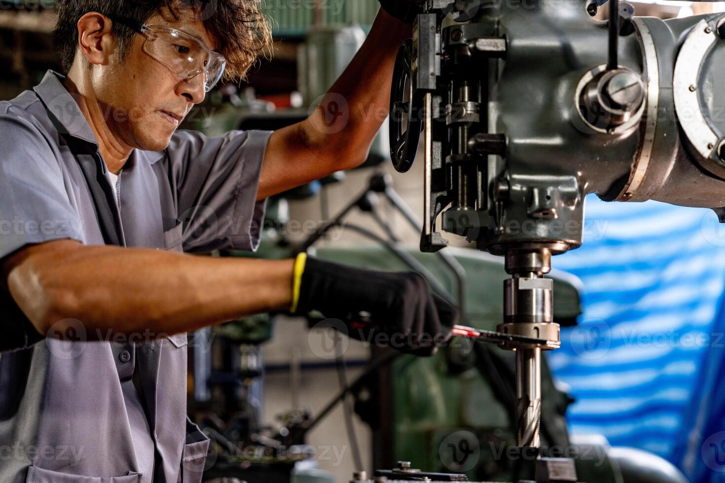 Engineer worker in production plant drilling at machine. Professional worker near drilling machine on factory. man inspecting and repairing machine for operation in workshop. photo