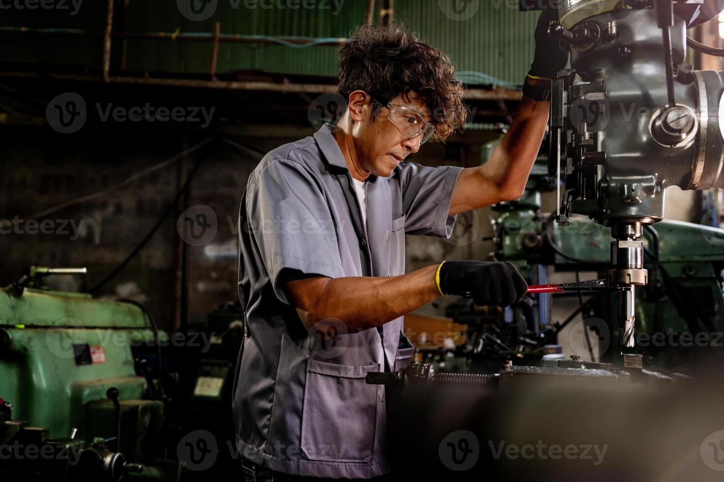 Engineer worker in production plant drilling at machine. Professional worker near drilling machine on factory. man inspecting and repairing machine for operation in workshop. photo