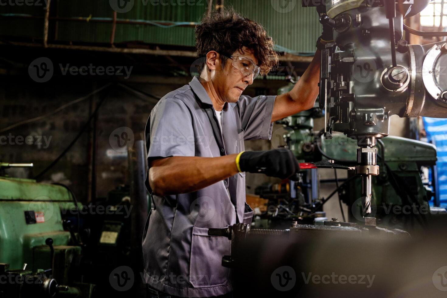 Engineer worker in production plant drilling at machine. Professional worker near drilling machine on factory. man inspecting and repairing machine for operation in workshop. photo