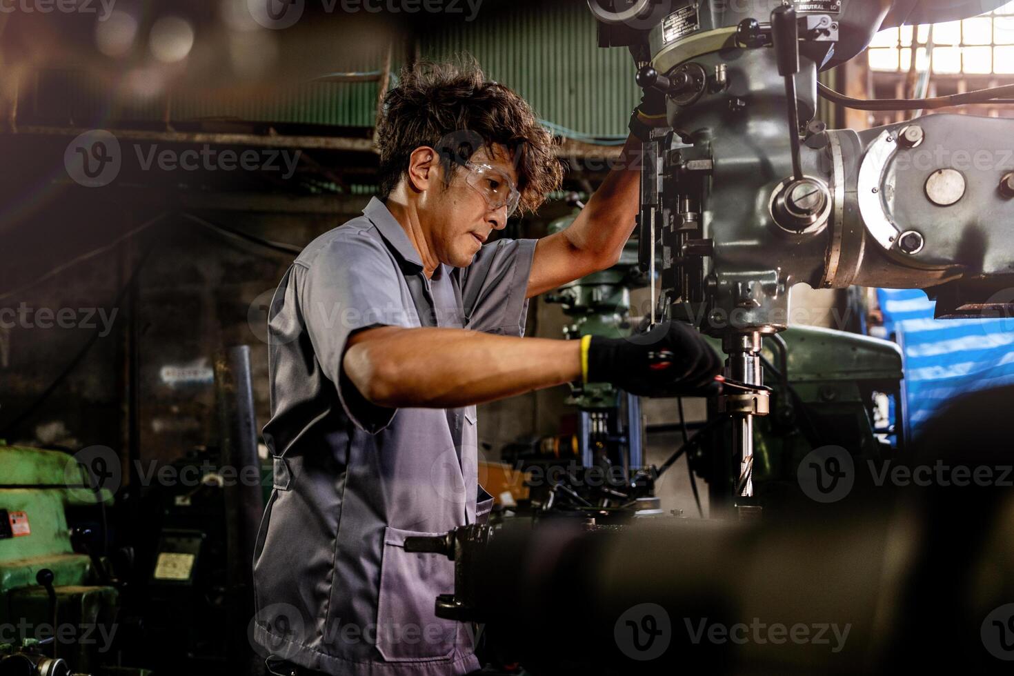 Engineer worker in production plant drilling at machine. Professional worker near drilling machine on factory. man inspecting and repairing machine for operation in workshop. photo