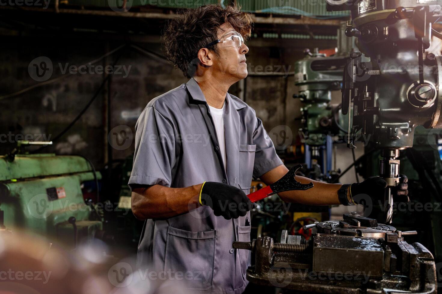 Engineer worker in production plant drilling at machine. Professional worker near drilling machine on factory. man inspecting and repairing machine for operation in workshop. photo