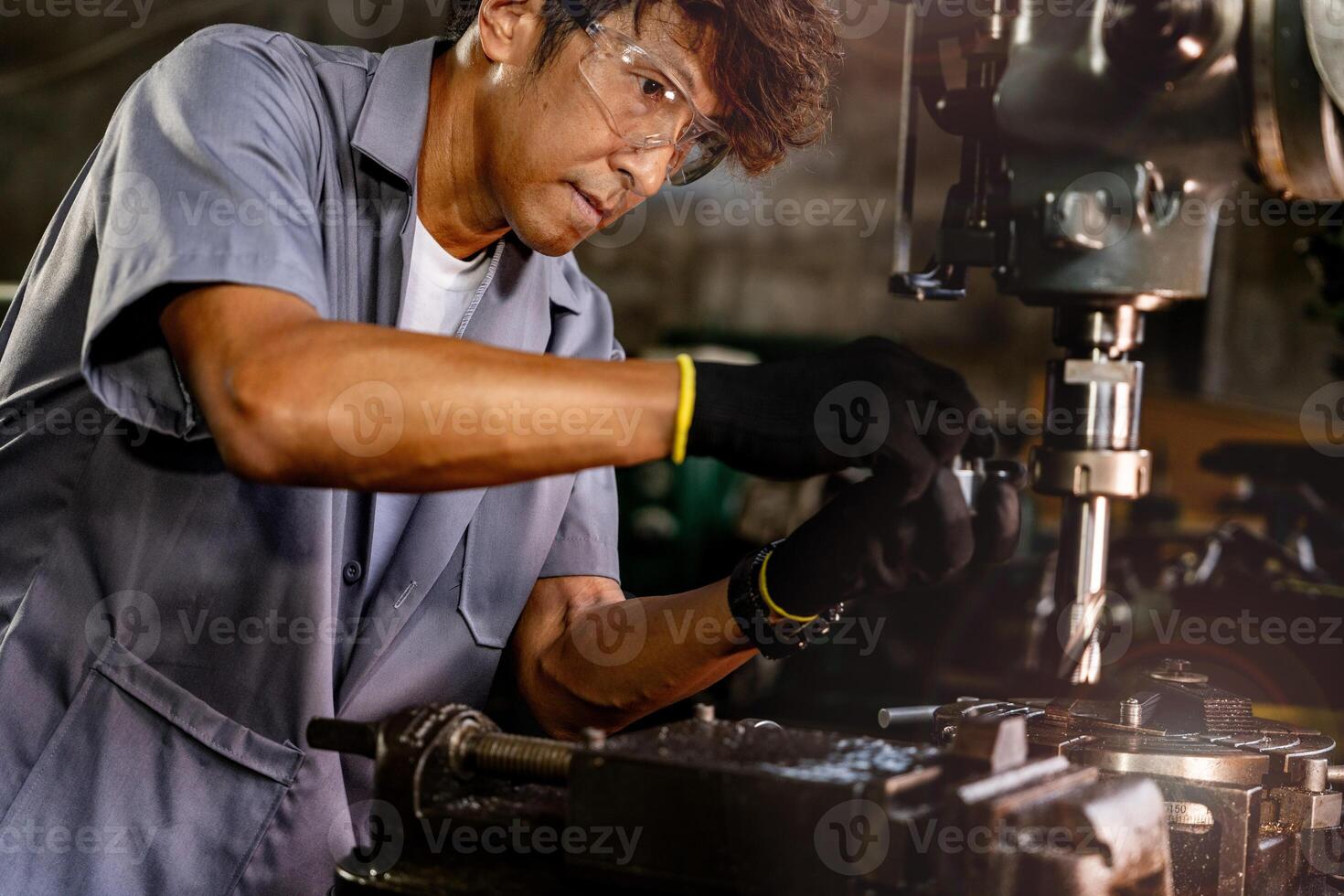 Engineer worker in production plant drilling at machine. Professional worker near drilling machine on factory. man inspecting and repairing machine for operation in workshop. photo