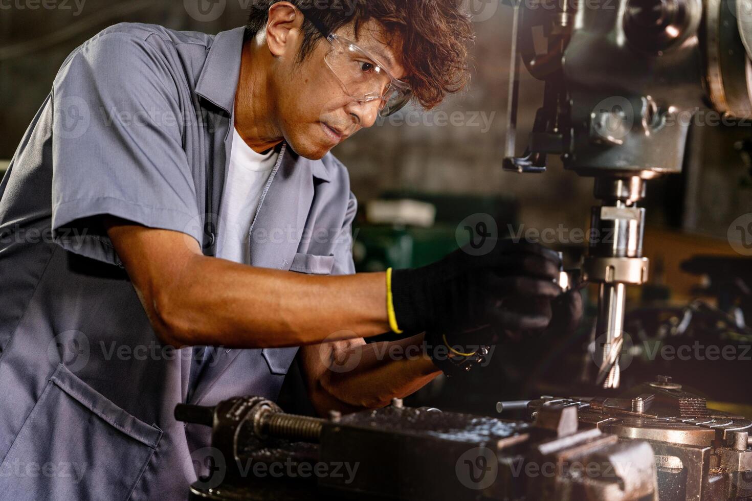 Engineer worker in production plant drilling at machine. Professional worker near drilling machine on factory. man inspecting and repairing machine for operation in workshop. photo