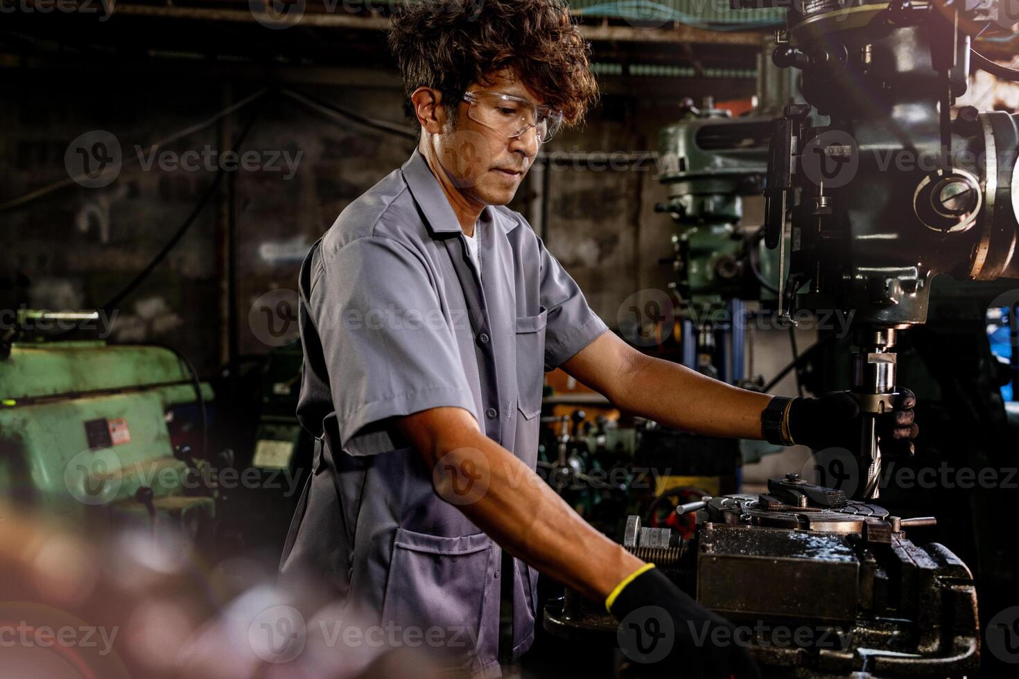 Engineer worker in production plant drilling at machine. Professional worker near drilling machine on factory. man inspecting and repairing machine for operation in workshop. photo