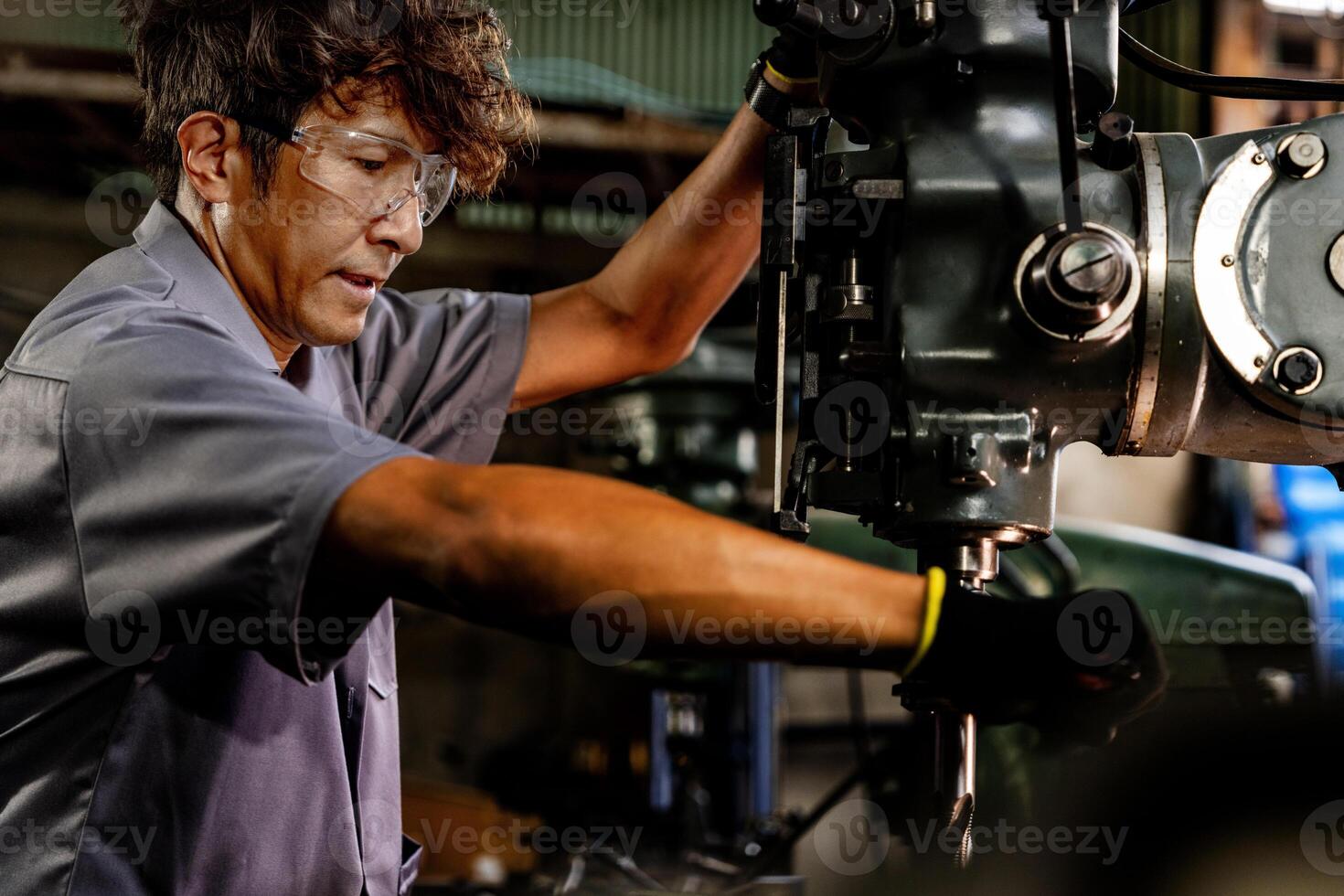 Engineer worker in production plant drilling at machine. Professional worker near drilling machine on factory. man inspecting and repairing machine for operation in workshop. photo