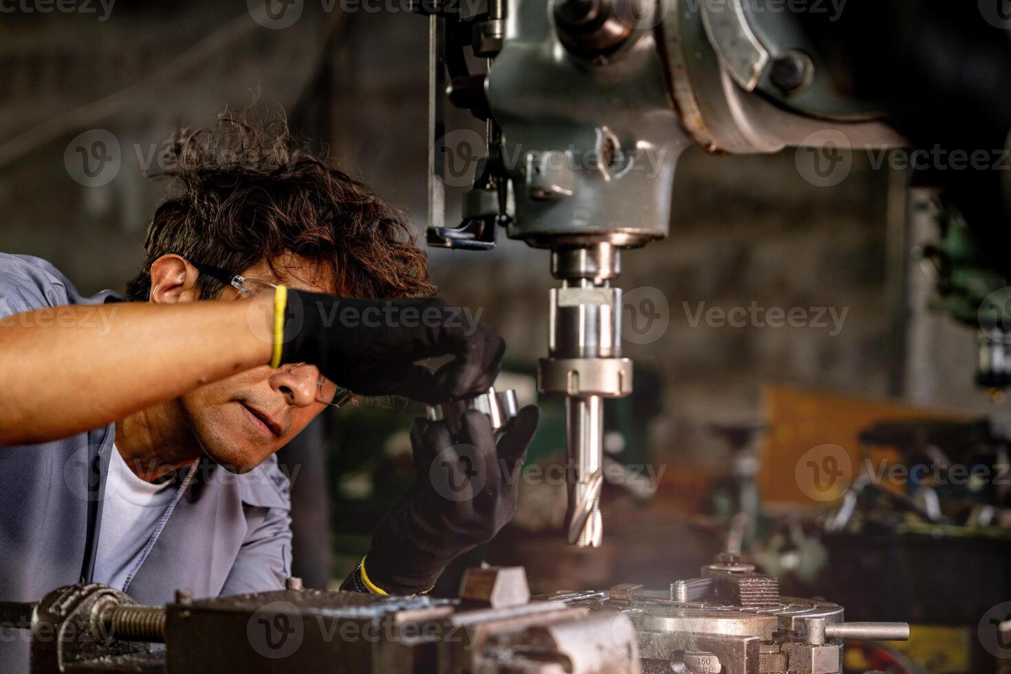 Engineer worker in production plant drilling at machine. Professional worker near drilling machine on factory. man inspecting and repairing machine for operation in workshop. photo