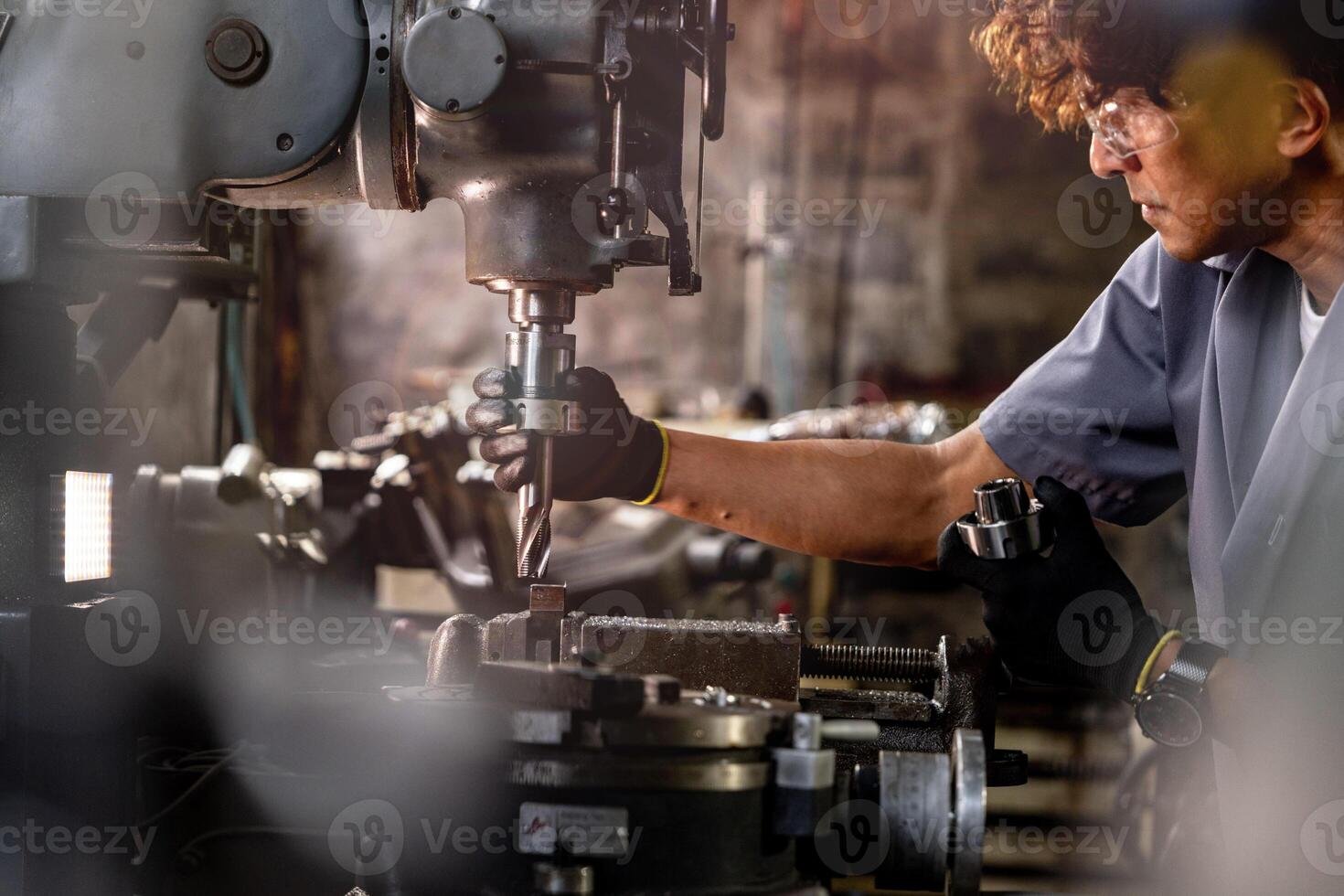 Asian worker in production plant drilling at machine. Professional worker near drilling machine on factory. finishing metal working internal steel surface on lathe grinder machine with flying sparks. photo