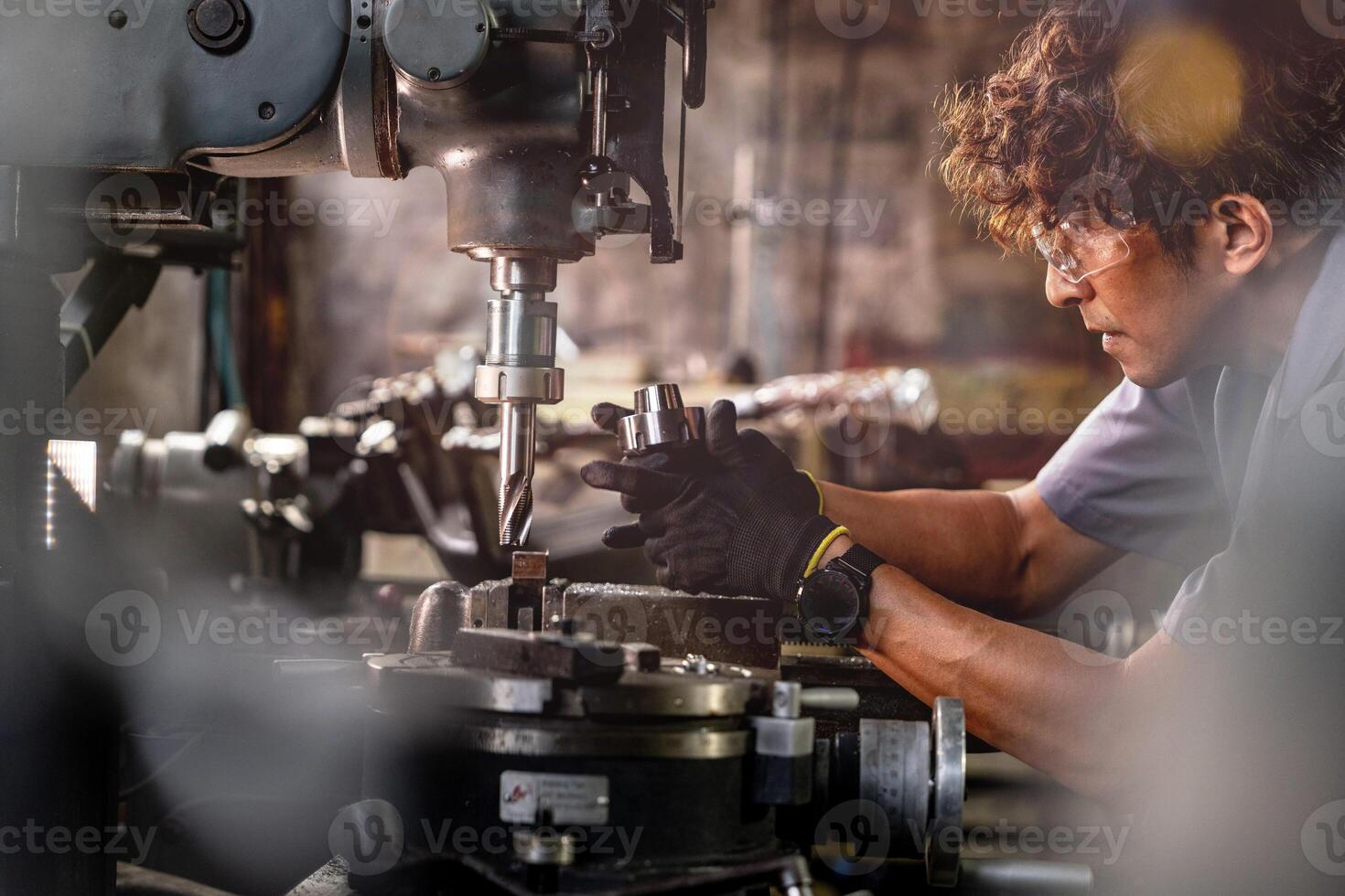 Asian worker in production plant drilling at machine. Professional worker near drilling machine on factory. finishing metal working internal steel surface on lathe grinder machine with flying sparks. photo