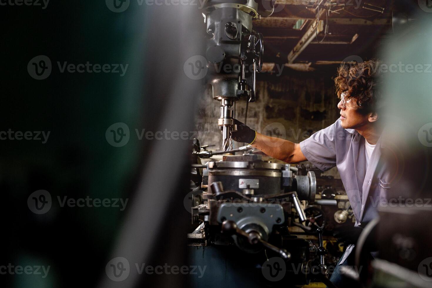 Asian worker in production plant drilling at machine. Professional worker near drilling machine on factory. finishing metal working internal steel surface on lathe grinder machine with flying sparks. photo