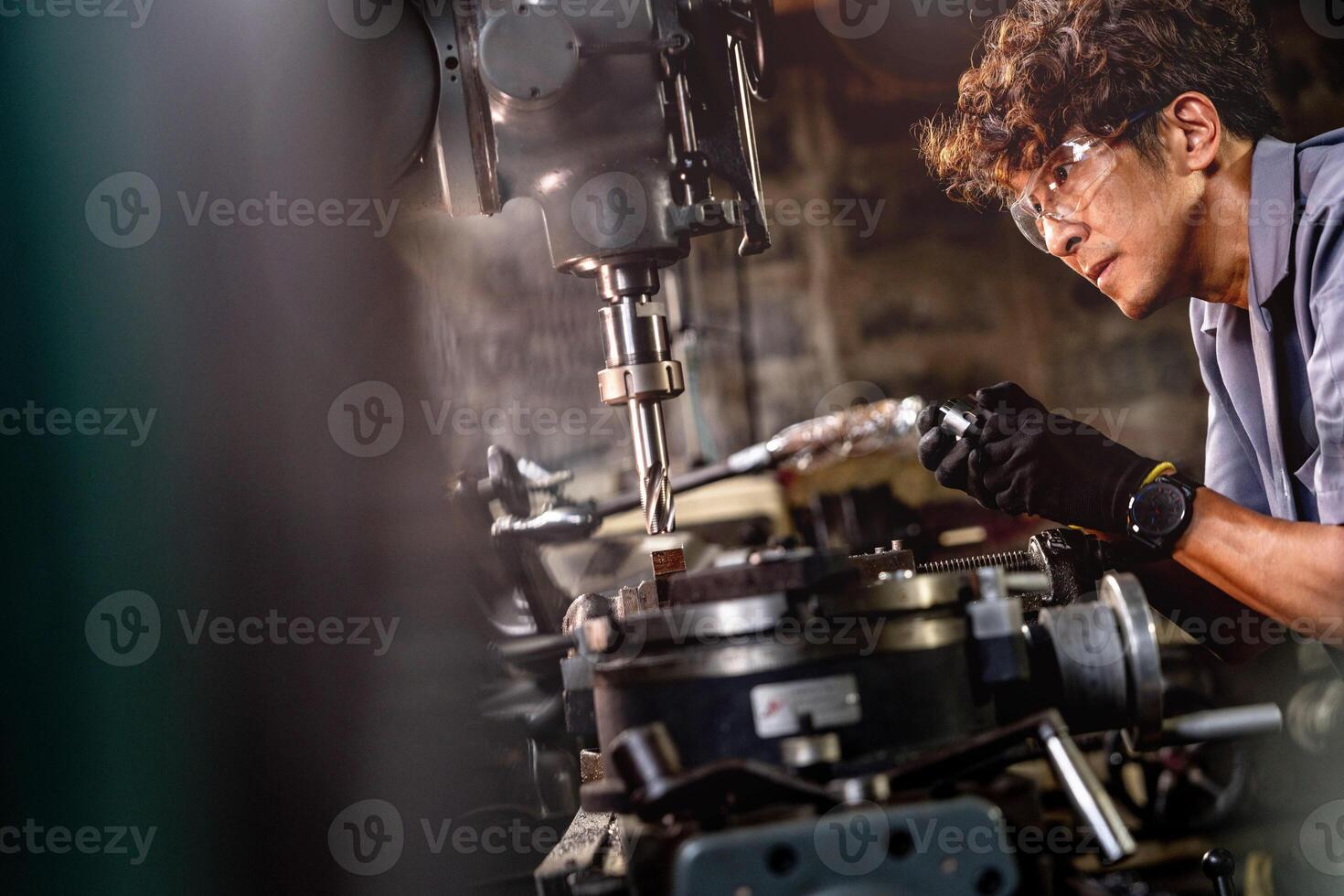 Asian worker in production plant drilling at machine. Professional worker near drilling machine on factory. finishing metal working internal steel surface on lathe grinder machine with flying sparks. photo