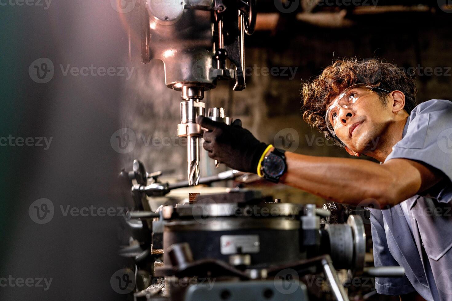 Asian worker in production plant drilling at machine. Professional worker near drilling machine on factory. finishing metal working internal steel surface on lathe grinder machine with flying sparks. photo