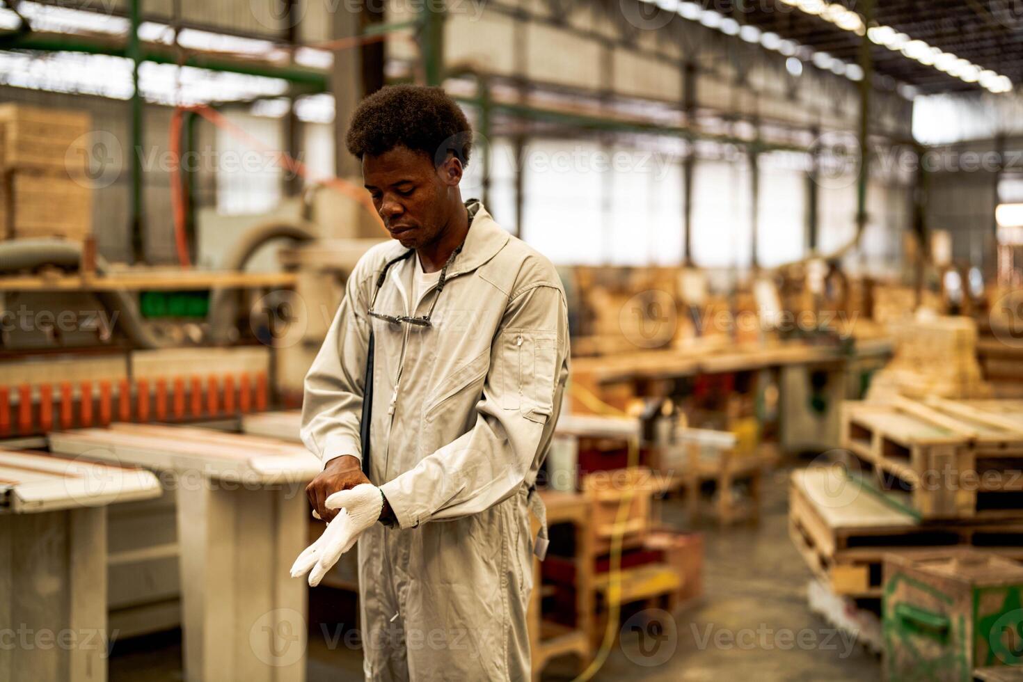 African man workers engineering standing with confidence with working suite dress and hand glove in front machine. Concept of smart industry worker operating. Wood factory produce wood palate. photo