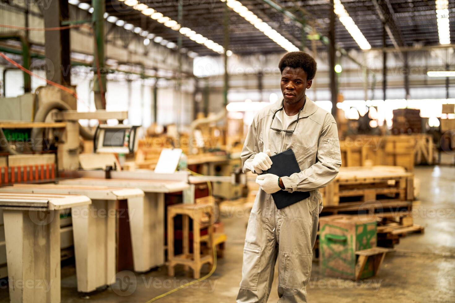 African man workers engineering standing with confidence with working suite dress and hand glove in front machine. Concept of smart industry worker operating. Wood factory produce wood palate. photo