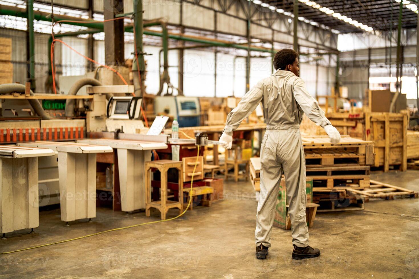 African man workers engineering standing with confidence with working suite dress and hand glove in front machine. Concept of smart industry worker operating. Wood factory produce wood palate. photo