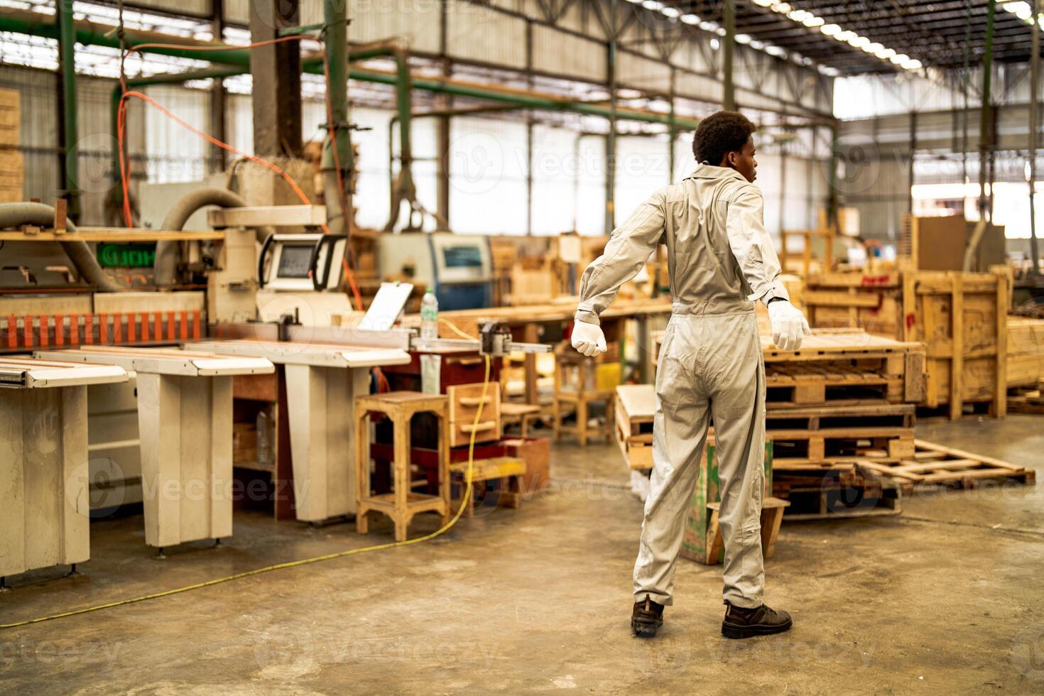 African man workers engineering standing with confidence with working suite dress and hand glove in front machine. Concept of smart industry worker operating. Wood factory produce wood palate. photo
