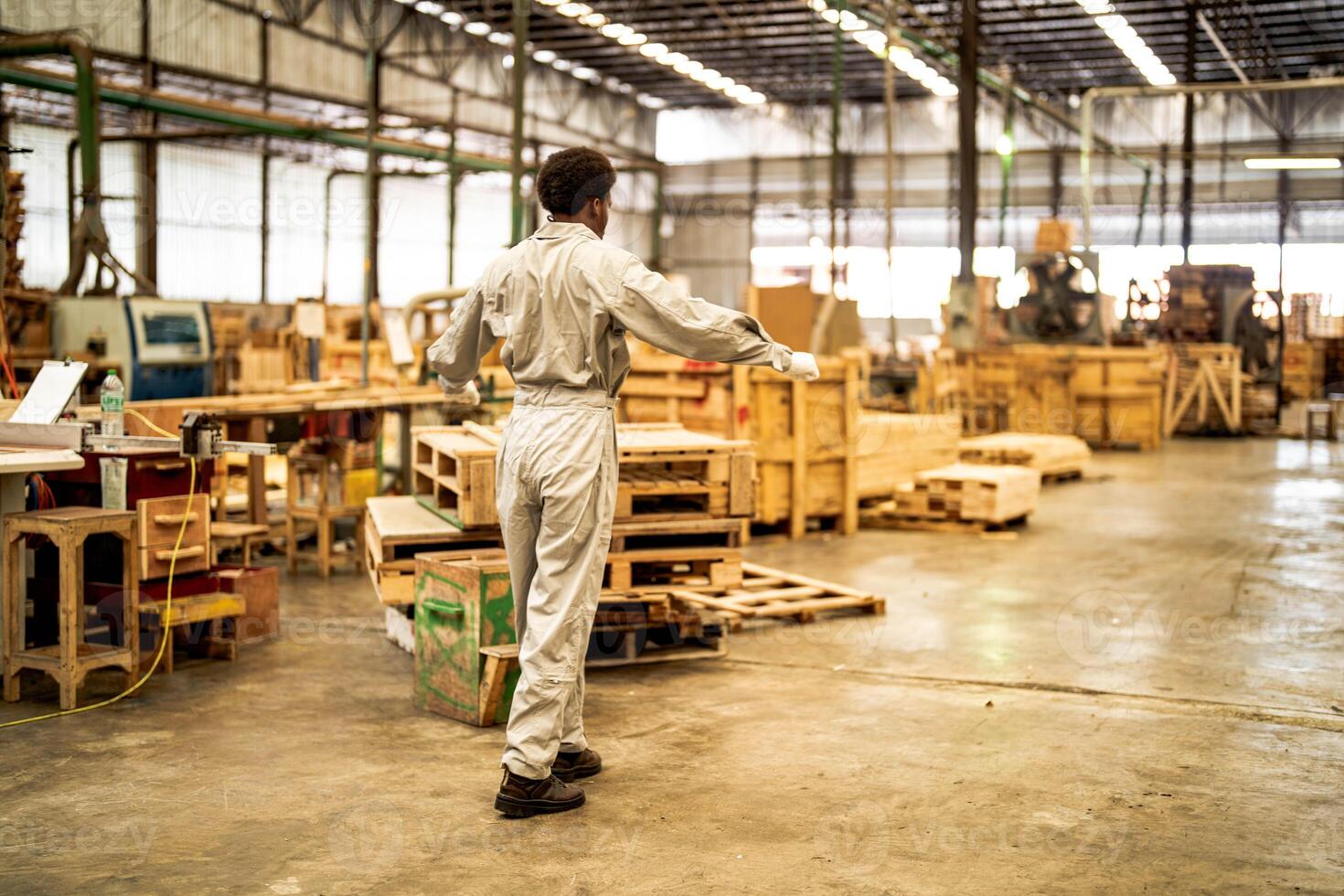 African man workers engineering standing with confidence with working suite dress and hand glove in front machine. Concept of smart industry worker operating. Wood factory produce wood palate. photo