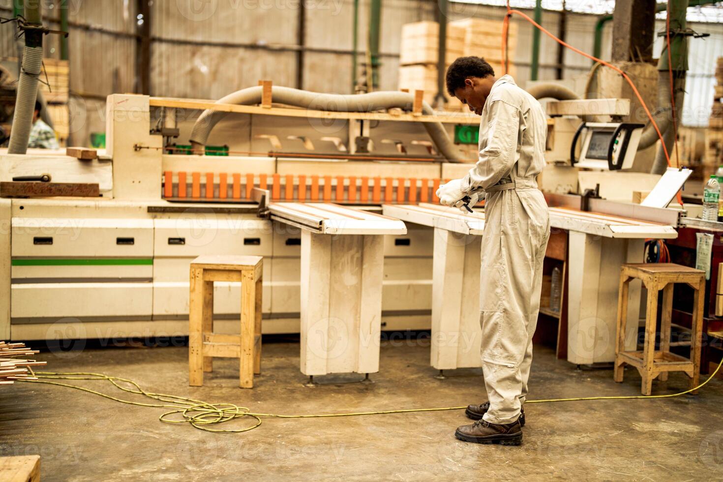 African man workers engineering standing with confidence with working suite dress and hand glove in front machine. Concept of smart industry worker operating. Wood factory produce wood palate. photo