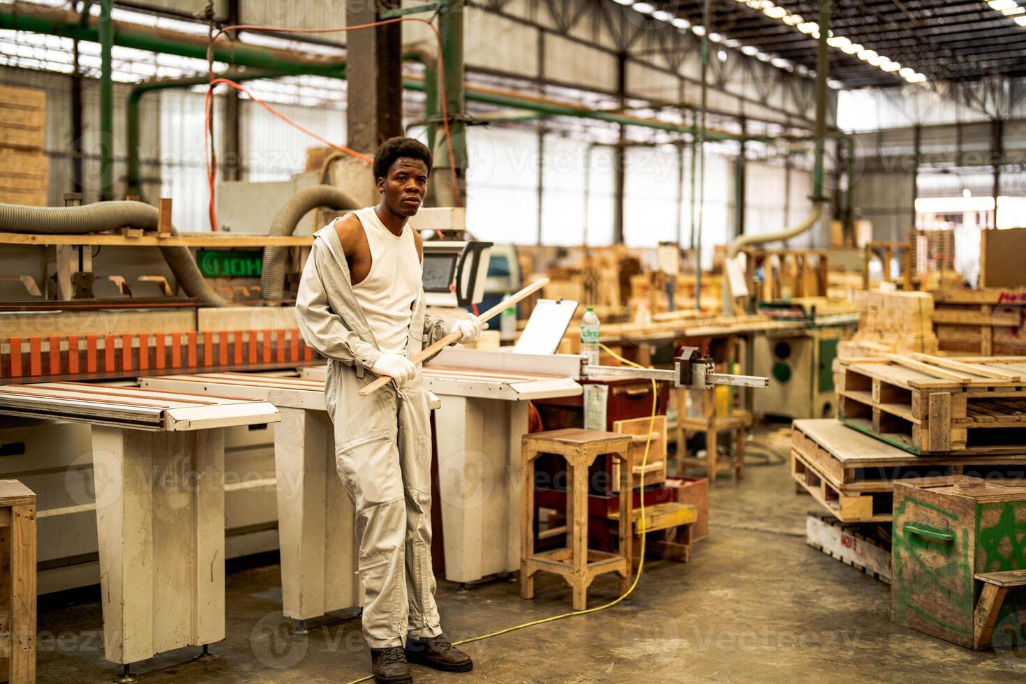 africano hombre trabajadores Ingenieria en pie con confianza con trabajando suite vestir y mano guante en frente máquina. concepto de inteligente industria trabajador operando. madera fábrica Produce madera paladar. foto