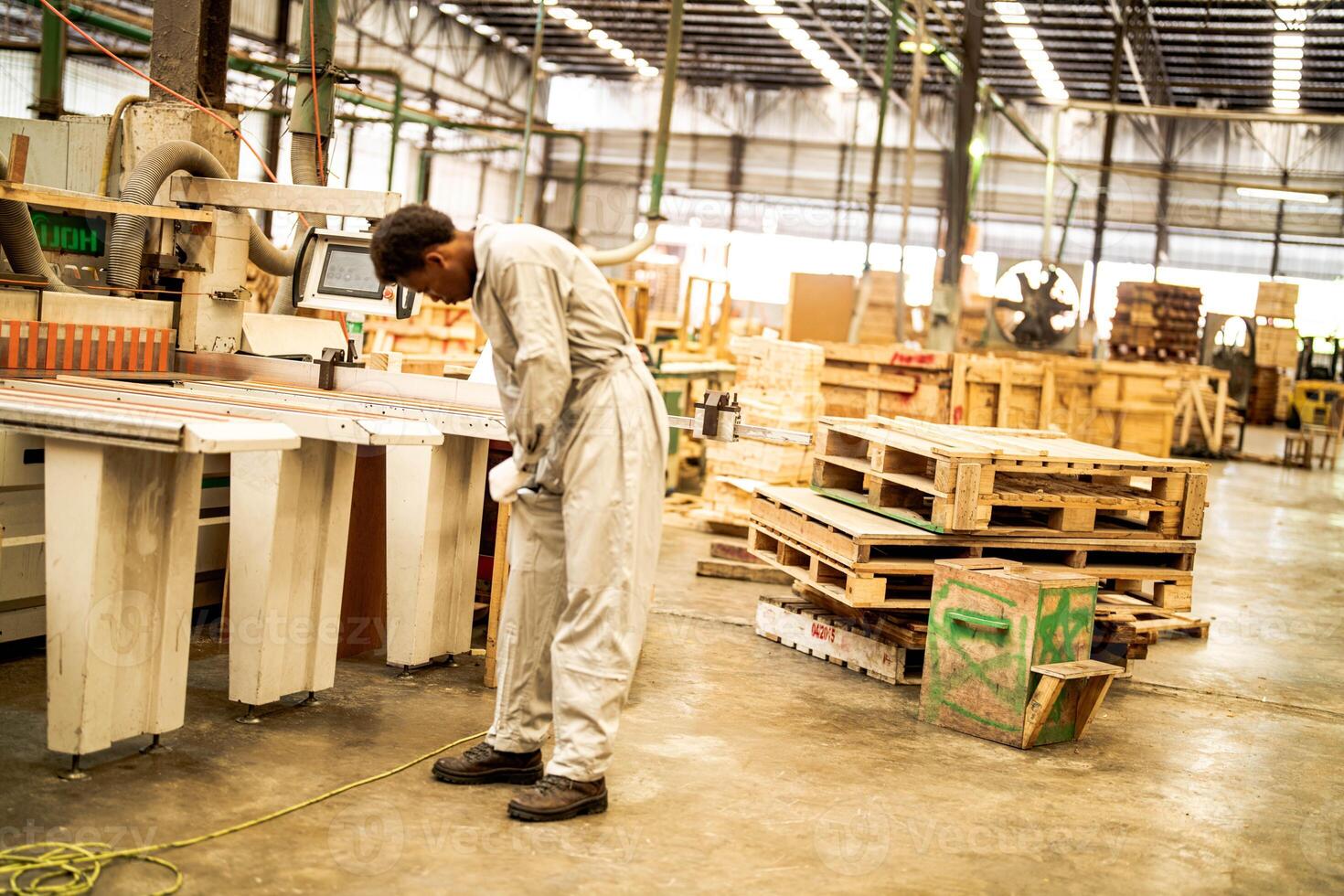 African man workers engineering standing with confidence with working suite dress and hand glove in front machine. Concept of smart industry worker operating. Wood factory produce wood palate. photo