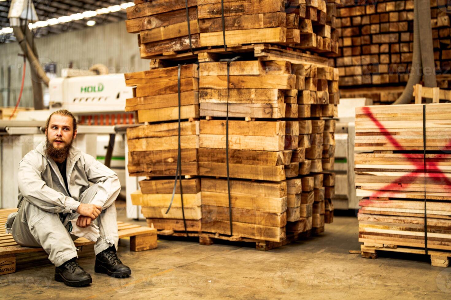 man workers engineering sitting with confidence with working suite dress and hand glove in front machine. Concept of smart industry worker operating. Wood factory produce wood palate. photo